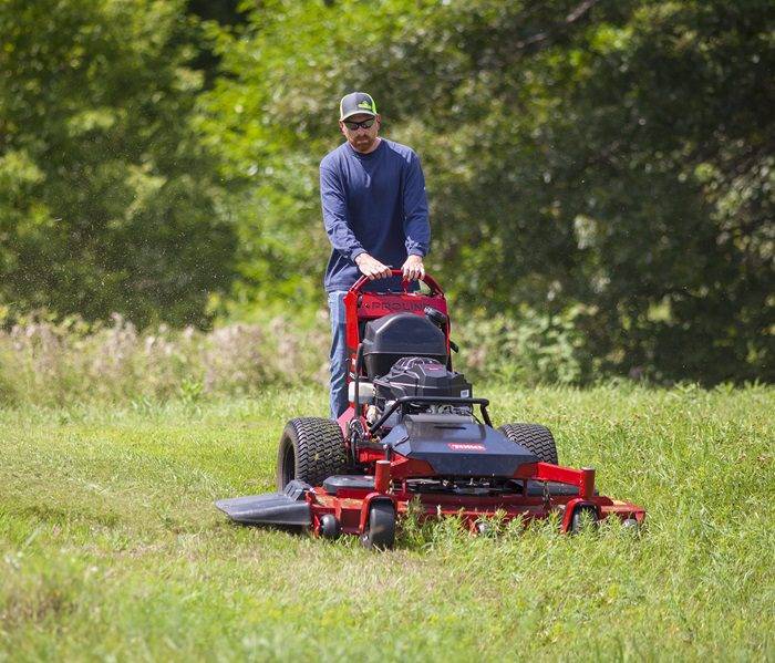 Gardening Professional at Work with Riding Mower Person mowing green grass with a heavy-duty riding mower.