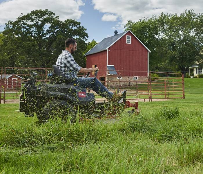 Lawn Mowing Service with Gas Mower Landscaping professional mowing a well-kept lawn with a riding mower.